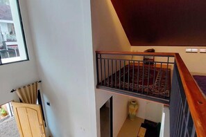 A staircase with a wooden handrail and a metal railing, leading to a landing with a patterned rug. - Yustien Homestay Jogja 3 Bedroom - Entire House (Kasihan)