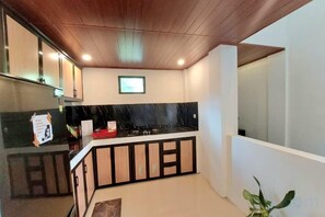 A kitchen with a black countertop, wooden cabinets, and a ceiling with recessed lighting. - Yustien Homestay Jogja 3 Bedroom - Entire House (Kasihan)