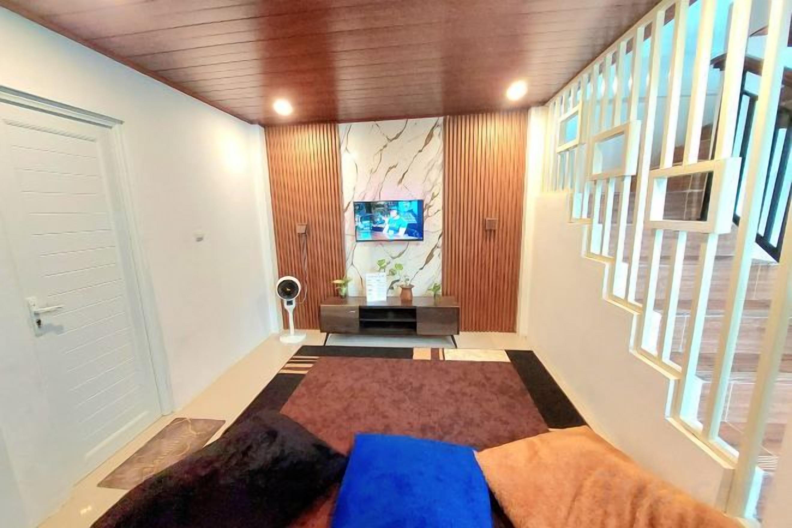 A hotel room with a bed, a television, a small table, and a decorative wall panel.