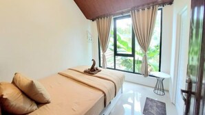 A single bed with a wooden headboard, a bedside table, and a window with curtains. - Yustien Homestay Jogja 3 Bedroom - Entire House (Kasihan)
