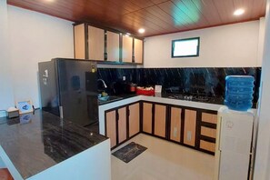 A kitchen with a refrigerator, stove, and water dispenser. - Yustien Homestay Jogja 3 Bedroom - Entire House (Kasihan)