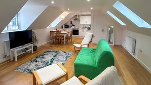 A spacious loft apartment with a high ceiling, skylights, a dining area, a kitchen, and a living room with seating. - Modern Studio in Chandlers Ford (Chandler's Ford)