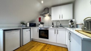 A modern kitchen with white cabinets, a built-in oven, a microwave, and a sink. - Modern Studio in Chandlers Ford (Chandler's Ford)