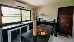 A modern kitchen with a window, a dining table, and a vase with dried plants. - Jayden Villas (Koh Phangan)