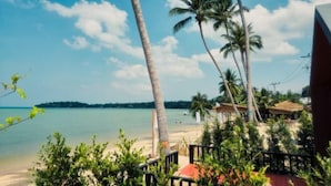 A beach view with palm trees, a clear sky, and a distant shoreline. - Jayden Villas (Koh Phangan)