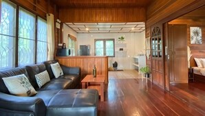 A wooden interior with a sofa, a small table, and a kitchen area. - Jayden Villas (Koh Phangan)
