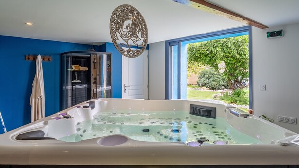 A modern bathroom with a large bathtub, a shower area, and a window with a view of greenery.