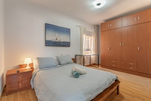 Un dormitorio con cama, mesita de noche y un armario grande.