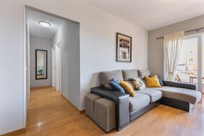 Una sala moderna con un sofá, un cuadro enmarcado y vistas a través de una ventana.