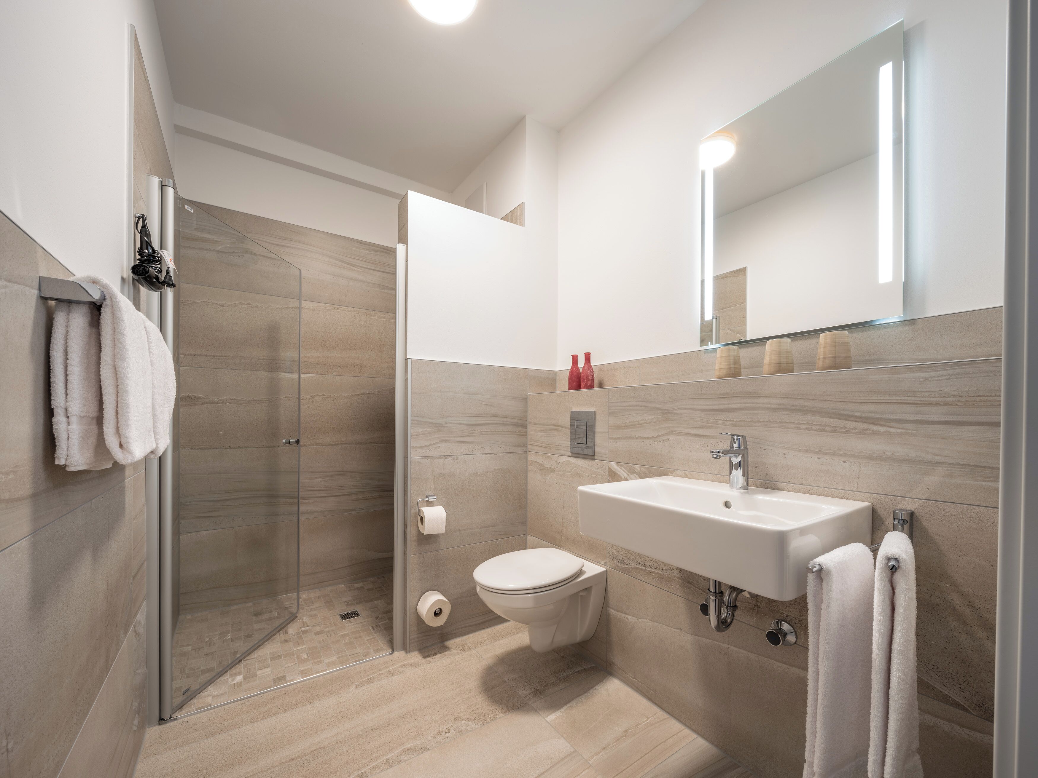 A modern bathroom with a glass shower enclosure, a toilet, and a sink with a mirror above it.
