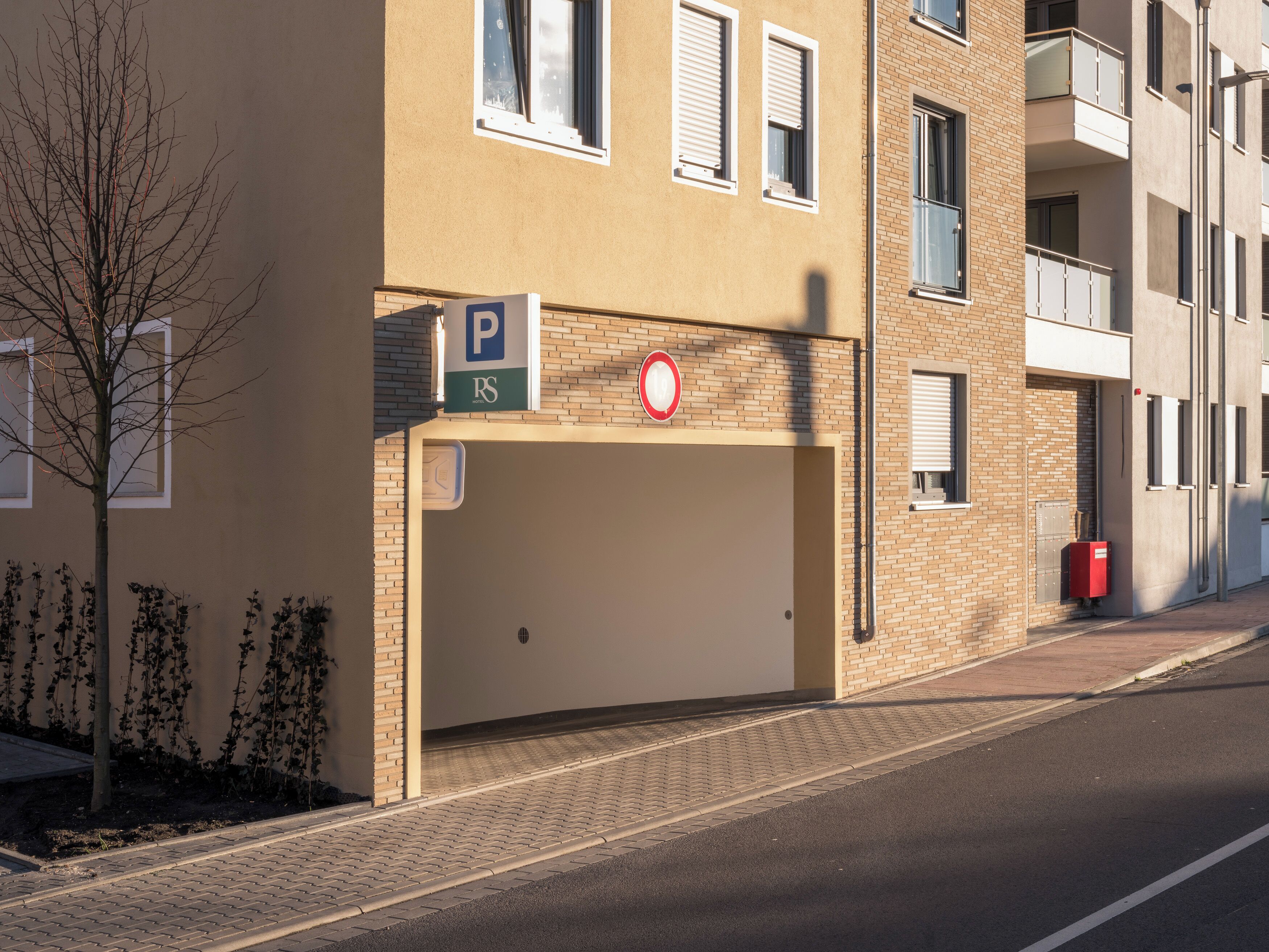 A building with a parking sign, a no parking sign, and a red mailbox.