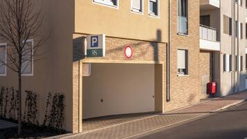 A building with a parking sign, a no parking sign, and a red mailbox.