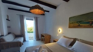 Una habitación de hotel con una cama grande, un sofá, una mesita y un cuadro en la pared.