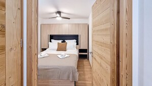 A narrow hallway leading to a bedroom with a bed, pillows, and a ceiling fan. - Le Framiré-appartement-4pers-Proche piste (Les Gets)