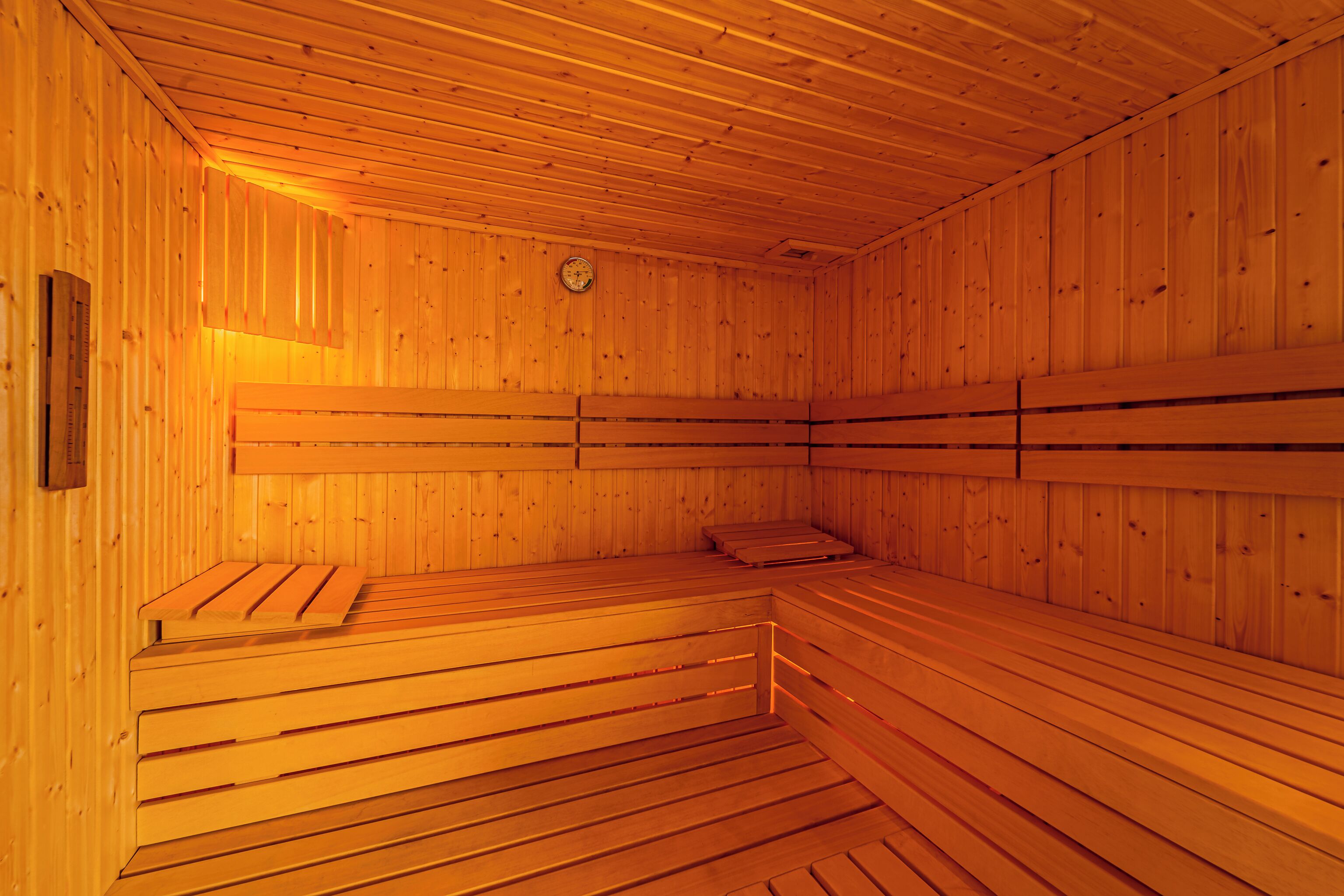 A sauna with wooden benches and a clock on the wall.