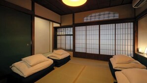 A traditional Japanese room with tatami flooring, shoji screens, and two tatami beds with pillows. - SAKON UKON (Kanazawa)