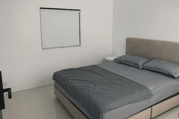 A bedroom with a bed, a nightstand, and a wall-mounted light. - 39 Haus (Bukit Mertajam)