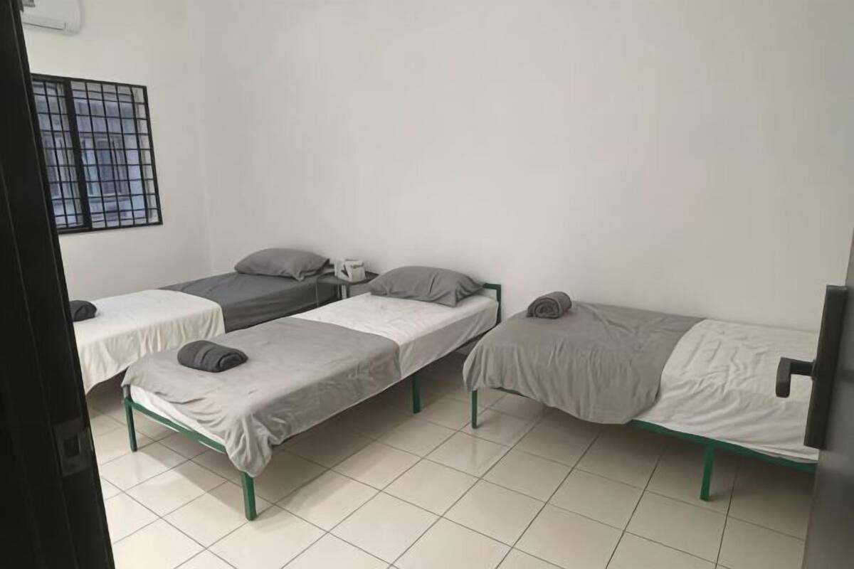 A room with three single beds, a window with bars, and a television.