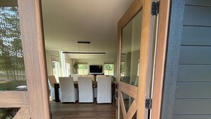 Une terrasse en bois mène à une cuisine moderne avec un coin repas.