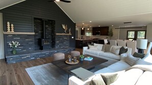 Uma sala de estar moderna com lareira, um sofá grande, uma mesa de centro e um espaço para refeições.