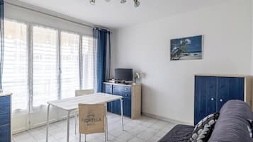 Un ambiente compatto con un tavolo da pranzo, un divano, una TV e un quadro appeso al muro.