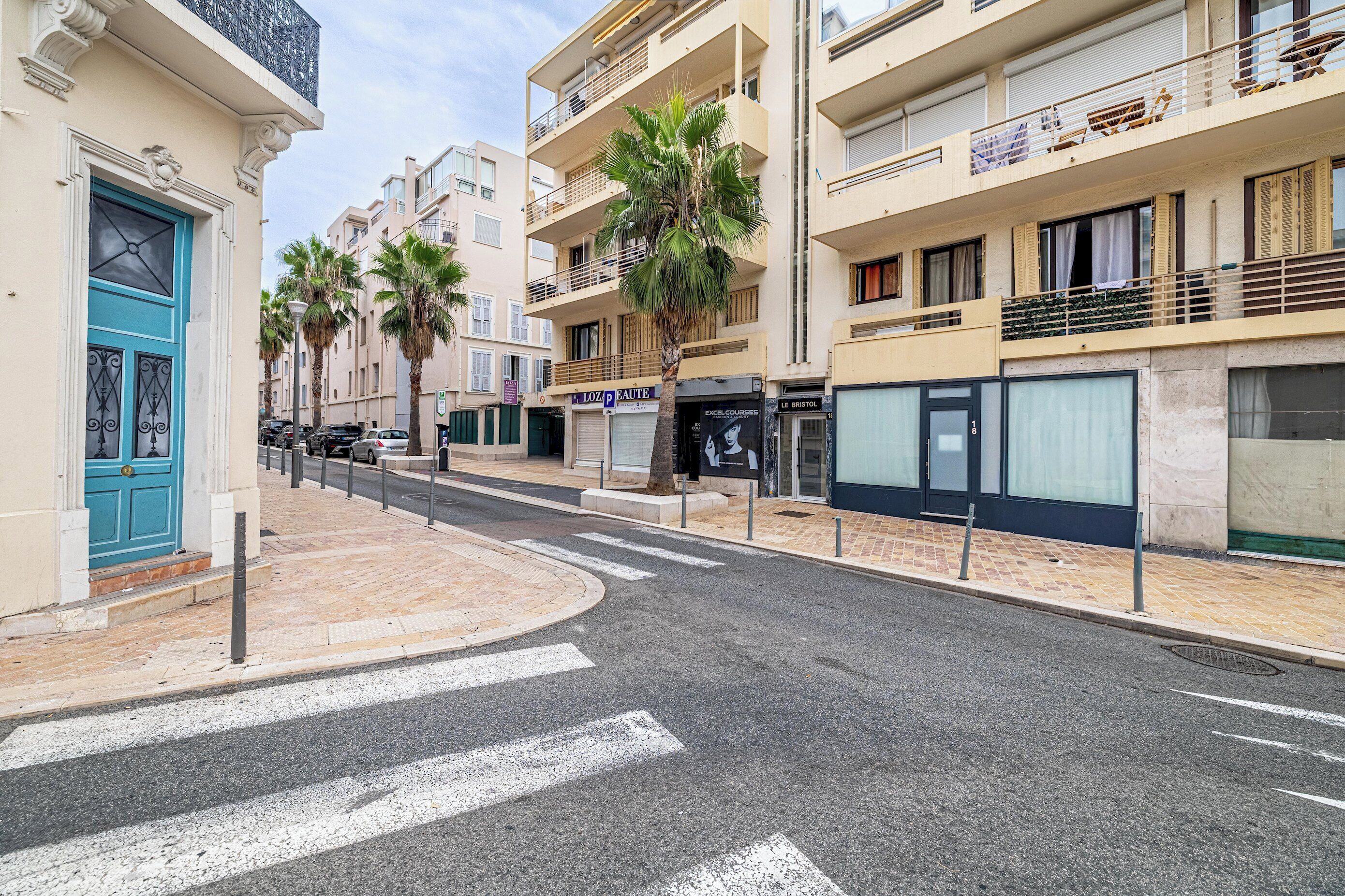 A street with buildings, palm trees, and a blue door.