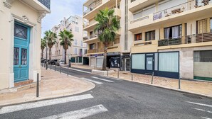 A street view with a blue door, palm trees, and multi-story buildings with balconies.