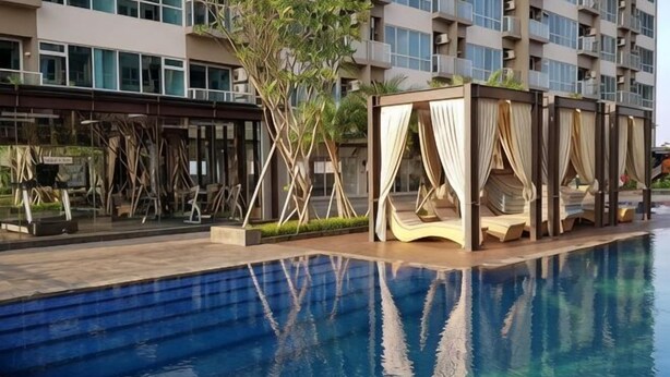 Ein Schwimmbad mit Holzterrasse und überdachter Sitzgelegenheit.