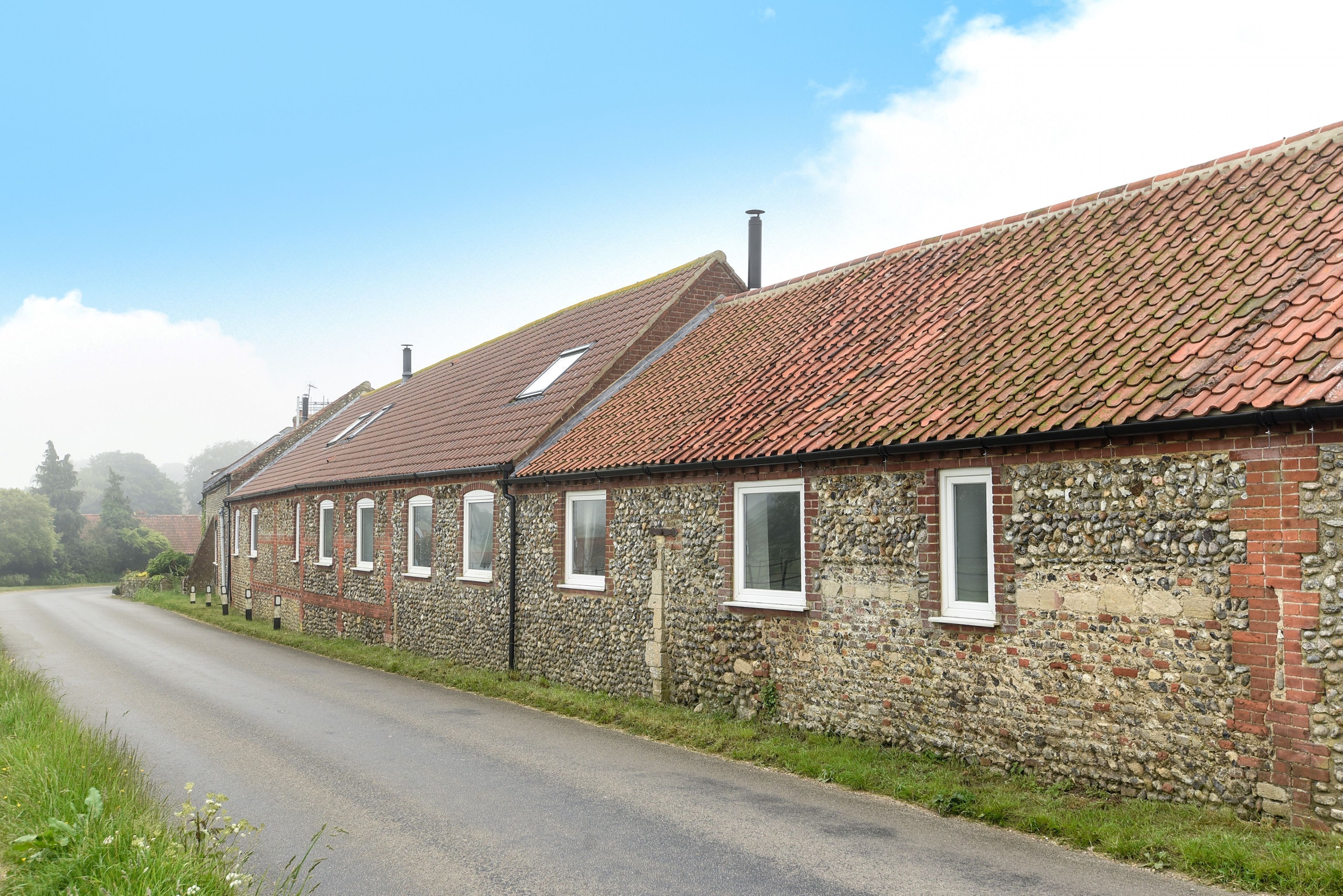 A row of stone buildings with red-tiled roofs and multiple windows.