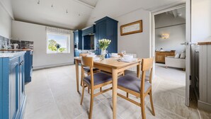 Een moderne keuken met blauwe kastjes, een eettafel met stoelen en uitzicht op het buitengebied.
