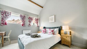 Een slaapkamer met een bed, nachtkastje, lamp en uitzicht.