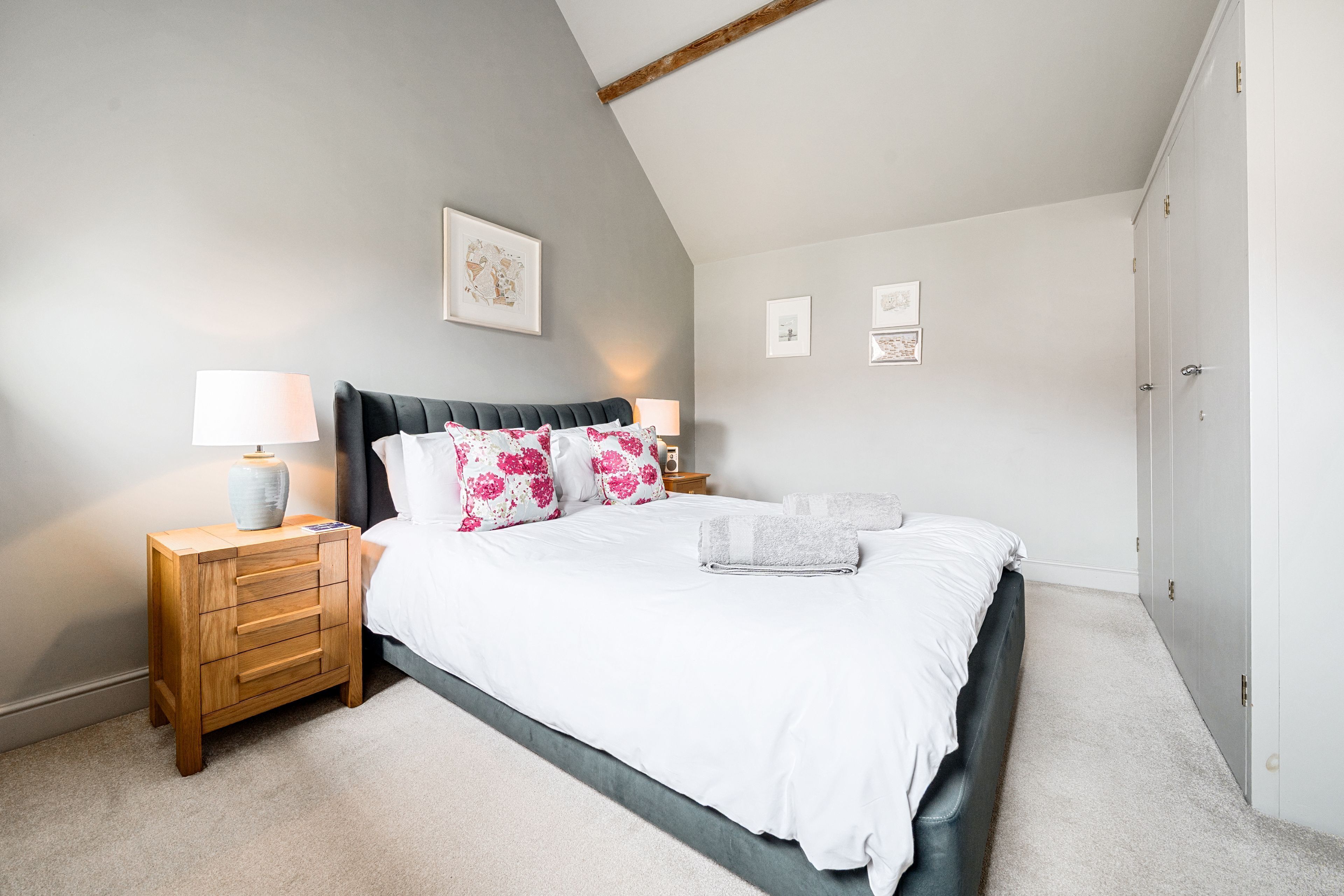 Une chambre à coucher comprenant un lit, des tables de chevet, une commode et une armoire.