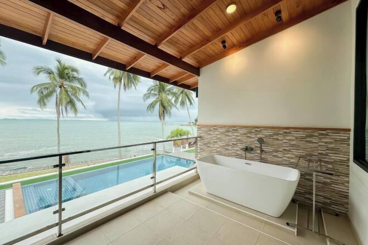 Une salle de bain moderne avec une baignoire sur pieds, un mur d’accent en pierre et une vue sur l’océan.