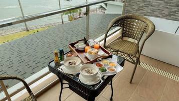 Varanda com mesa posta para o café da manhã, com vista para um corpo d'água.