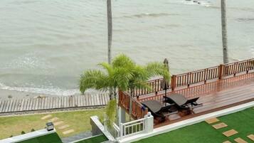 A deck with a view of the sea, a small garden area, and a seating arrangement.
