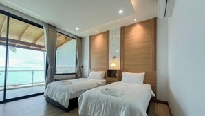 A hotel room with two beds, a large window with a view of the sea, and a wooden ceiling.