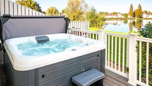 A hot tub on a deck with a view of a lake and trees. - Windrush Lake 20, Summit Lodge (P) - Lakeside Lodge, On-site Activites, Sleeps 7 (South Cerney)