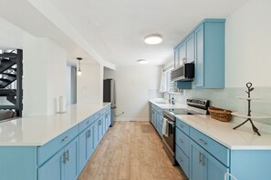 Una cocina moderna con armarios azules, encimeras blancas y electrodomésticos de acero inoxidable.