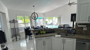 A modern kitchen with white cabinets, a granite countertop, and a built-in dishwasher.