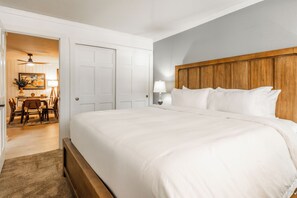 Ein Schlafzimmer mit einem großen Bett, einem Holz-Kopfteil, einem Schreibtisch mit Stuhl und einem Deckenventilator.