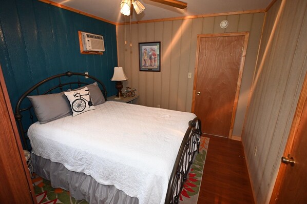 A bedroom with a bed, a nightstand, a lamp, and a door.