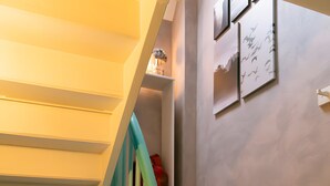 A staircase with wooden steps and a green handrail, leading to a room with a door and a window.