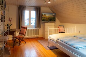 Ein Schlafzimmer mit einem Bett, einem Sessel, einer Heizung, einem Fenster und einem Bild an der Wand.