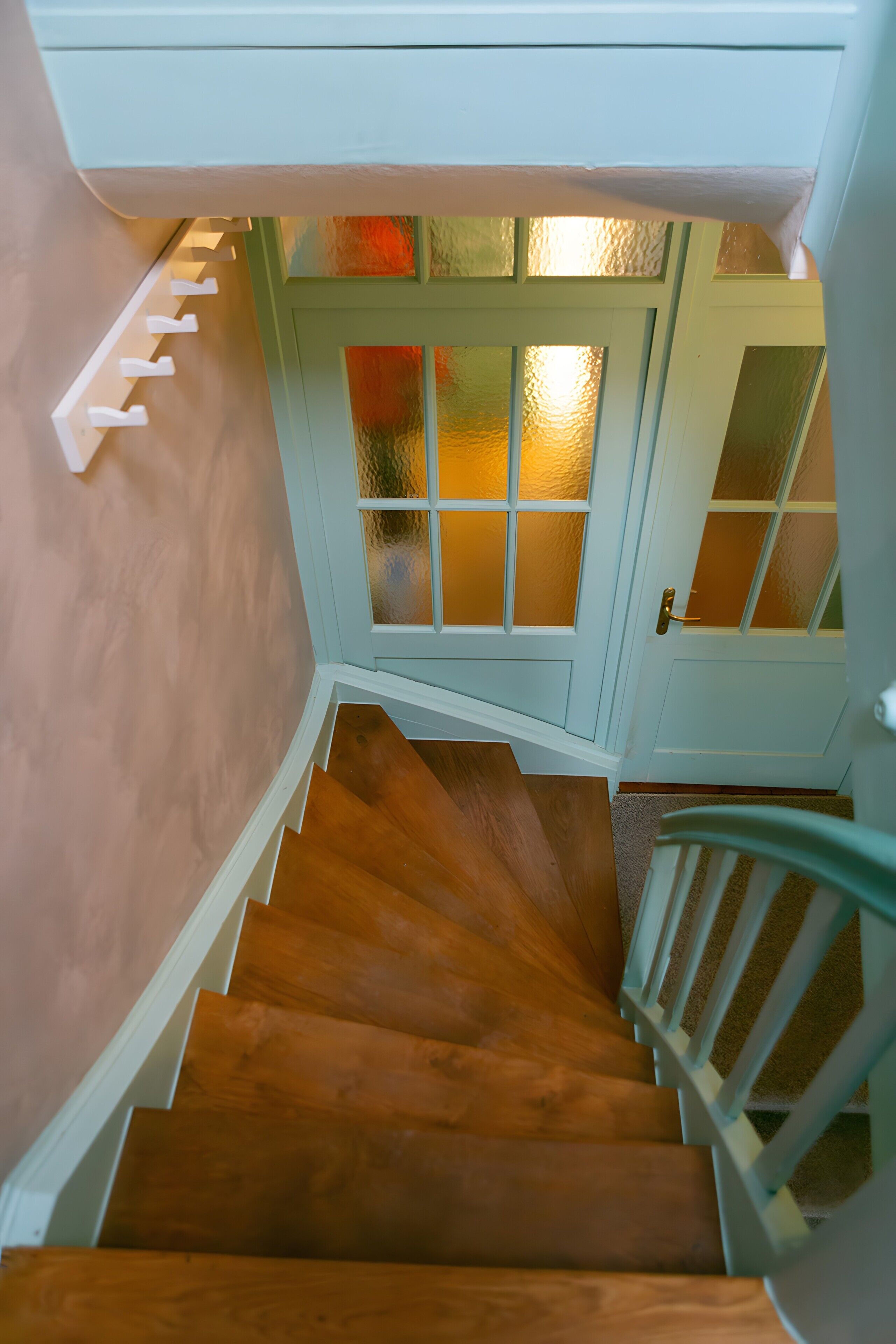 A wooden staircase leading to a room with a door featuring frosted glass panels.
