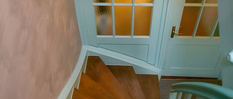 A wooden staircase leading to a room with a door featuring frosted glass panels.