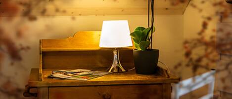 A wooden desk with a lamp, a potted plant, and a magazine.