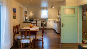 A cozy kitchen with a dining table, chairs, and a light green door.