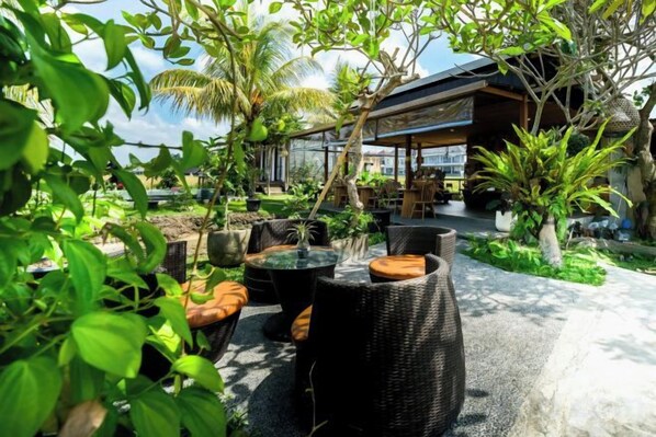 An outdoor seating area with wicker furniture and a view of a building. - Ubud Jungle Stay - Mahari by WAHM (Bali)