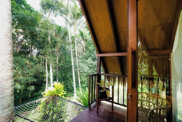 A wooden balcony with a view of a lush garden and tall trees. - Ubud Jungle Stay - Mahari by WAHM (Bali)