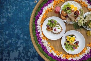 Un montaje para comer con platos de comida, una bebida y un arreglo decorativo de flores.